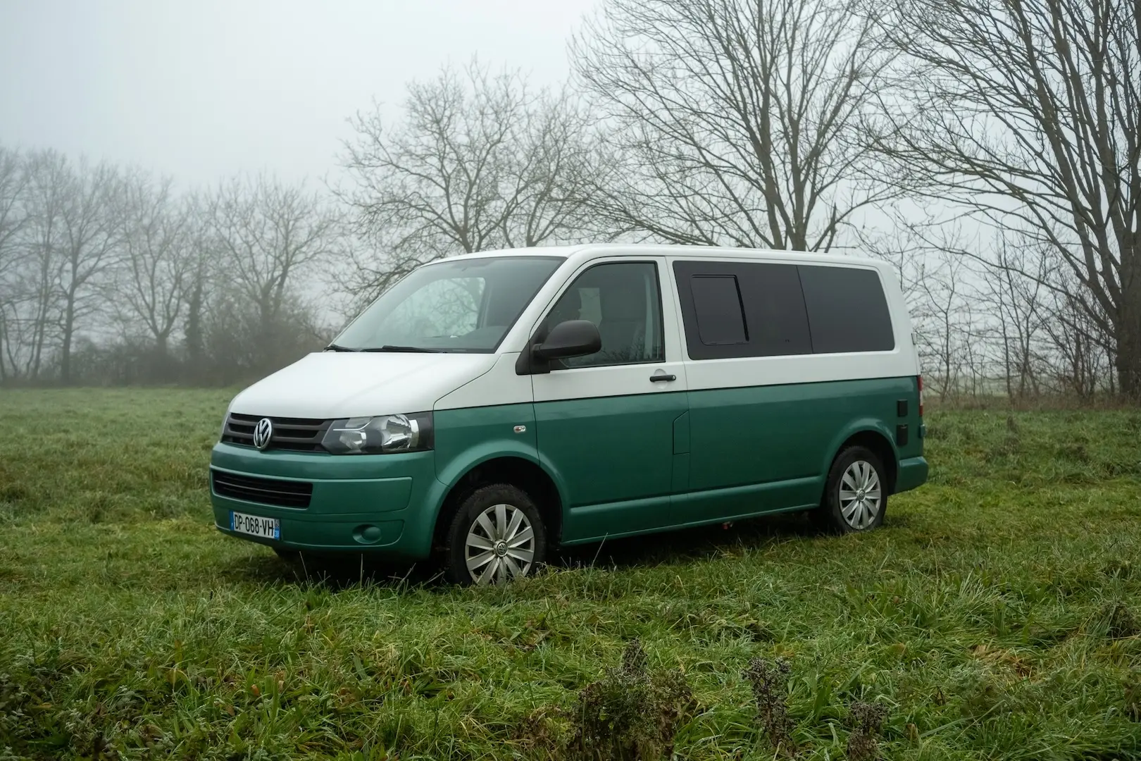 photo d'un van aménagé bleu et bleu canard garé sur de l'herbe